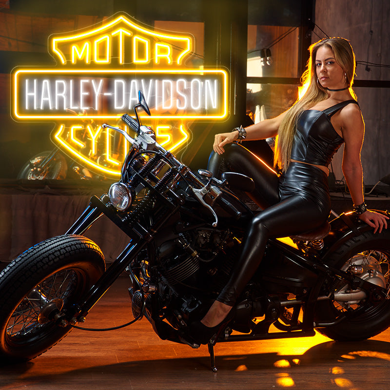 Harley Davidson neon sign logo in the colors golde yellow and white. Installed on wall. Hot girl posing with her motorbike infront of neon sign.