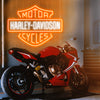 Harley Davidson neon sign in the colors orange and white. Installed on wall above red motorbike. 